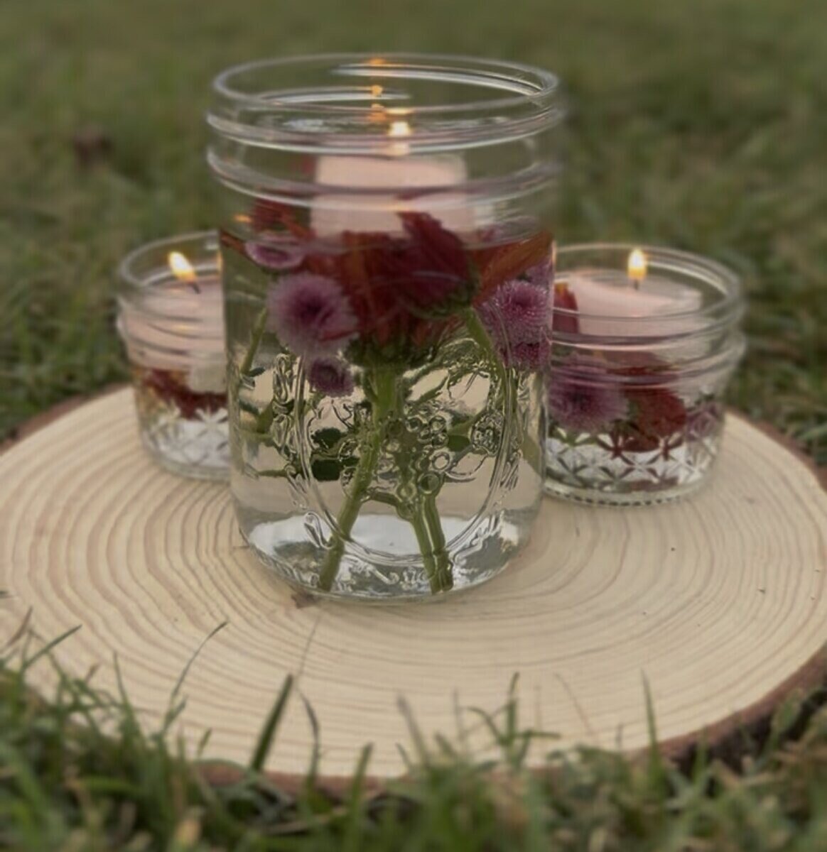 Flower-filled candles glowing on the grass during a RETURN gathering