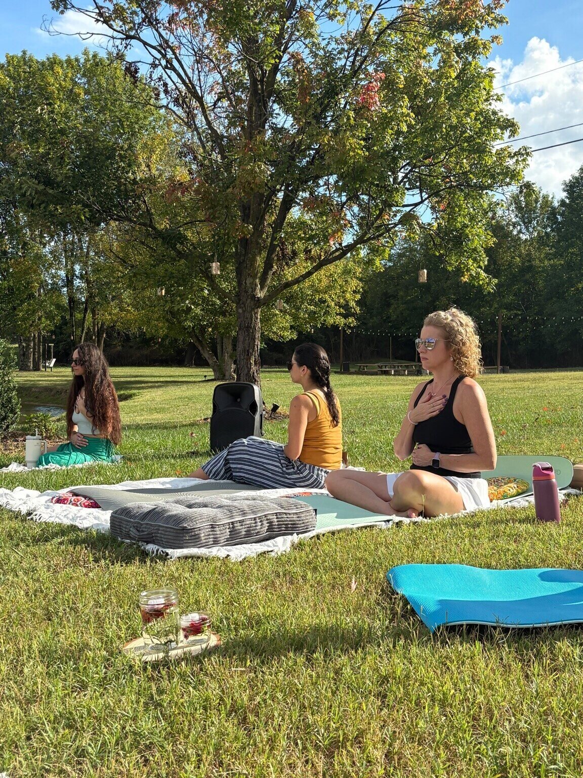 Three guests seated on the grass with hands held gently to their hearts