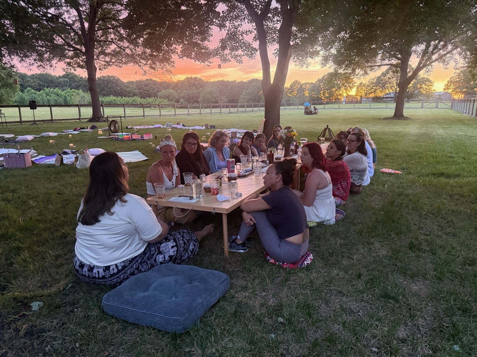 Guests gathered around a low communal table beneath a glowing sunset
